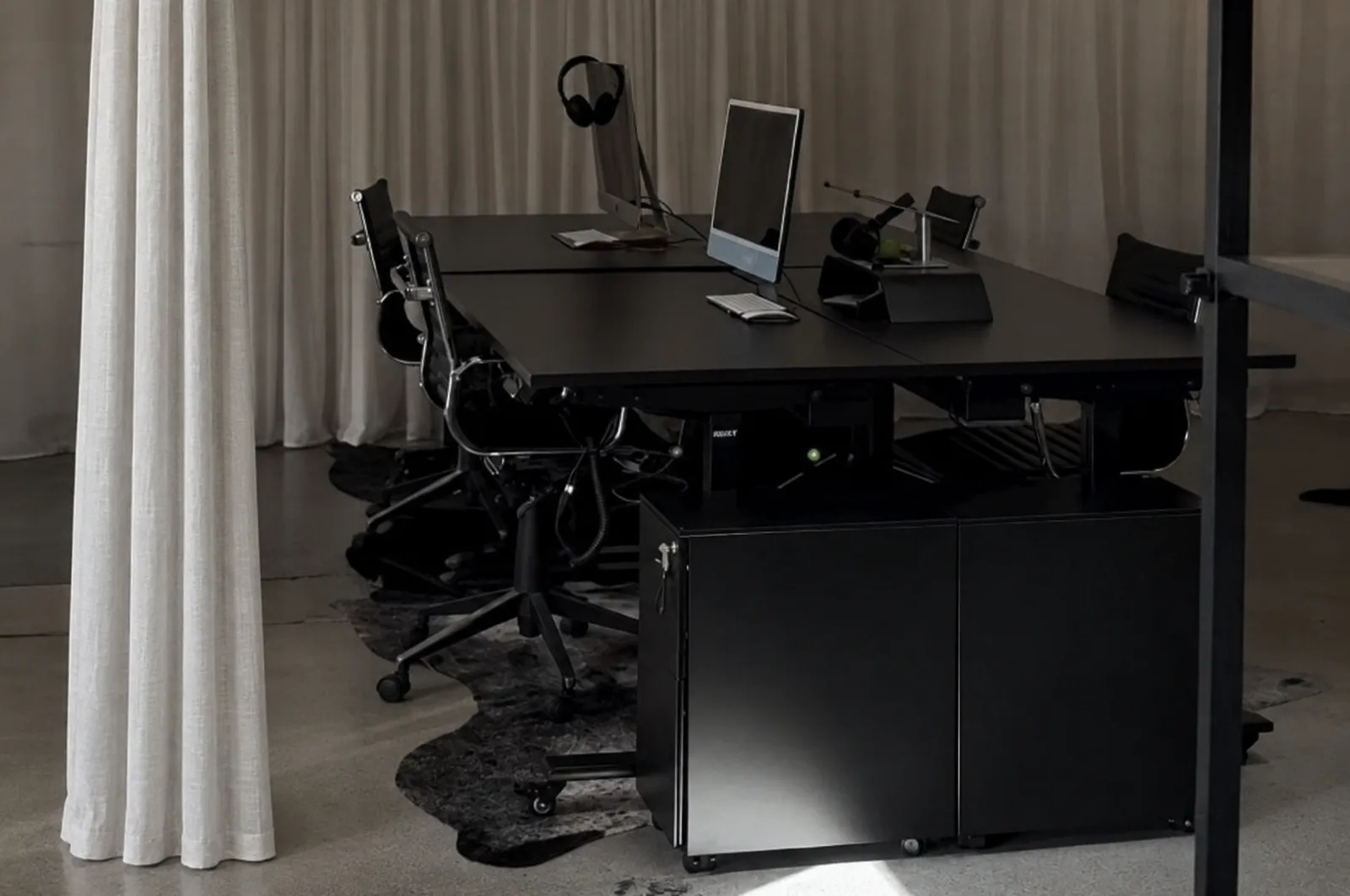 Black workstations framed by linen curtains in the Eugénie Michael Lawyers office