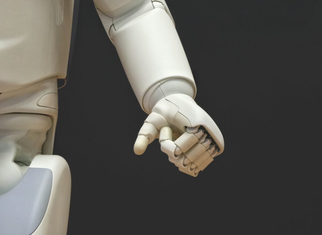 A white robotic hand reaching forward against a dark background